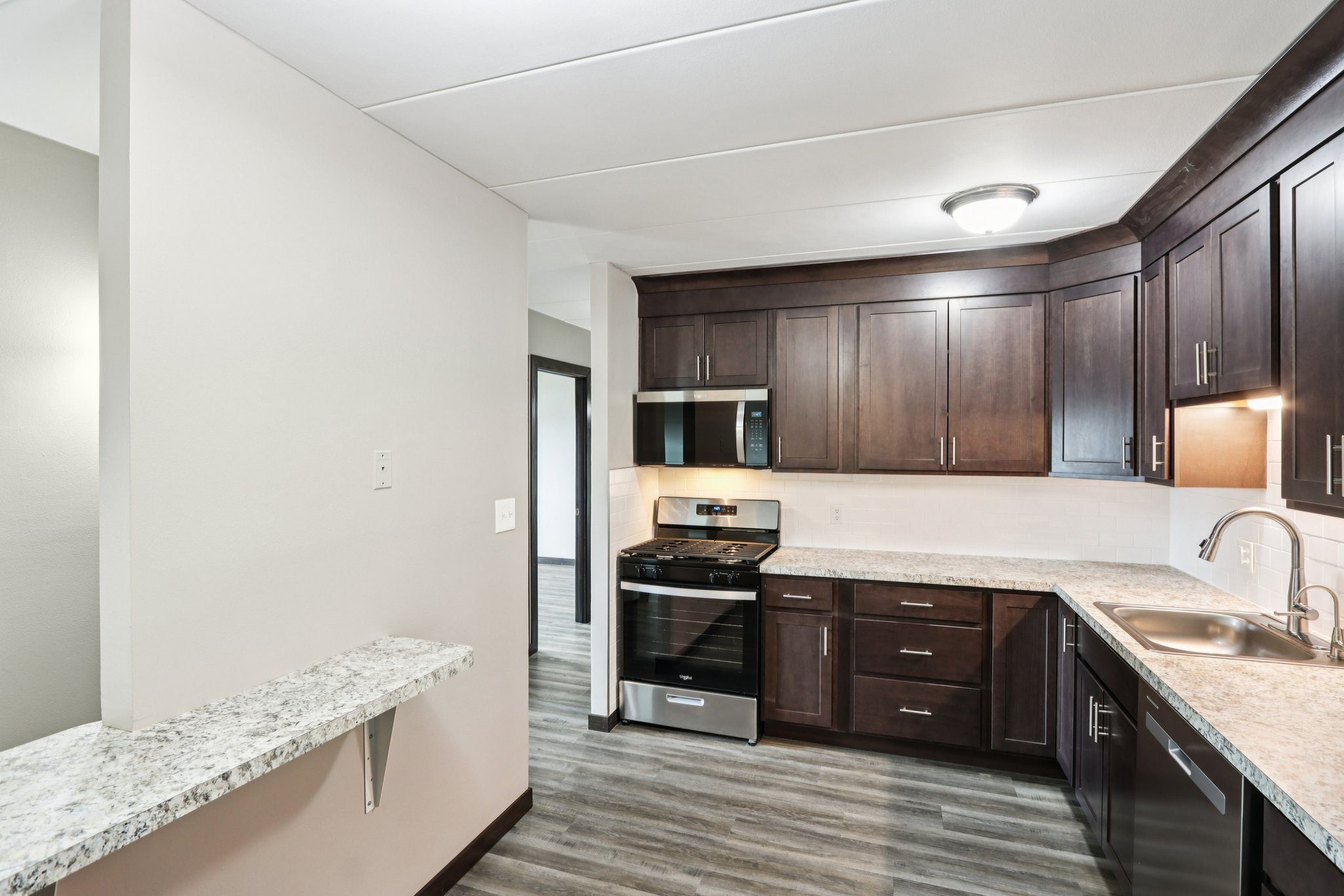 A kitchen with dark brown cabinets and a marble countertop.